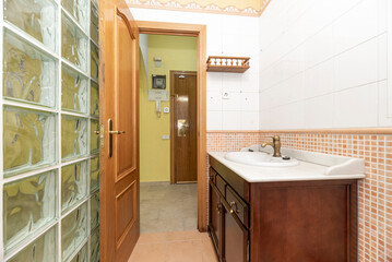 Nice bathroom with dark wood furniture, white marble top, translucent glass paving wall and the other with brown tile