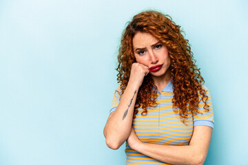 Young ginger caucasian woman isolated on blue background who feels sad and pensive, looking at copy space.