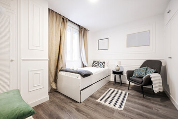 bedroom with single bed, bedside table, armchair with cushions, a jarapa on the floor and curtains on the windows