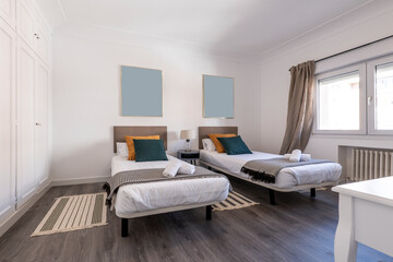 Bedroom with double beds, dark wood flooring, cushions, upholstered headboards and built-in wardrobe with white doors