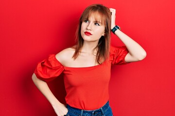 Redhead young woman wearing casual red t shirt confuse and wondering about question. uncertain with doubt, thinking with hand on head. pensive concept.