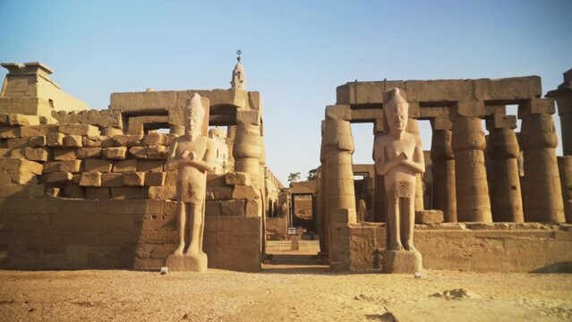 Large statues of Kings next to the Karnak Temple entrance in Luxor, Egypt.
Static shot with a bird flying across the sky.