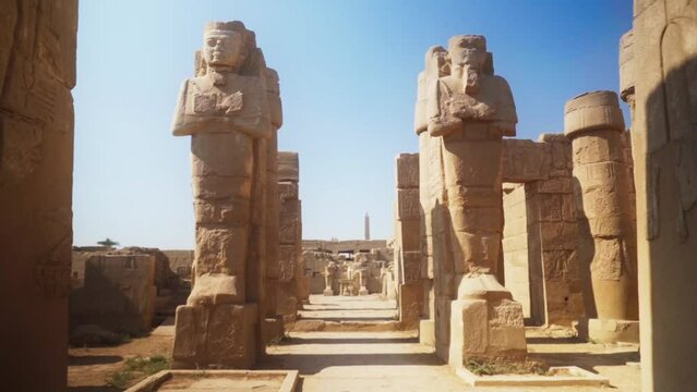 Two tall statues of kings in the Karnak Temple, Luxor Egypt. 
Static shot with blue sky. 