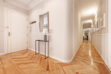 Entrance of a residential house with a large corridor with red varnished pine wood floors and...