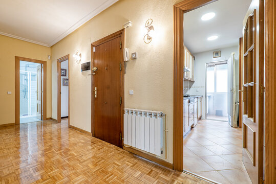 Hall of a residential house with aluminum radiator, parquet floors and entrance to a kitchen and a bathroom