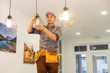 An electrician is installing spotlights on the ceiling