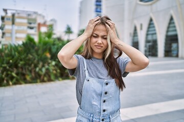 Fototapeta premium Young caucasian woman outdoors suffering from headache desperate and stressed because pain and migraine. hands on head.