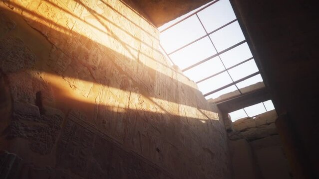 Light streaks shining on a wall with hieroglyphs through a roof window inside the Kamak Temple in Luxor, Egypt. 
Slow camera rotation 