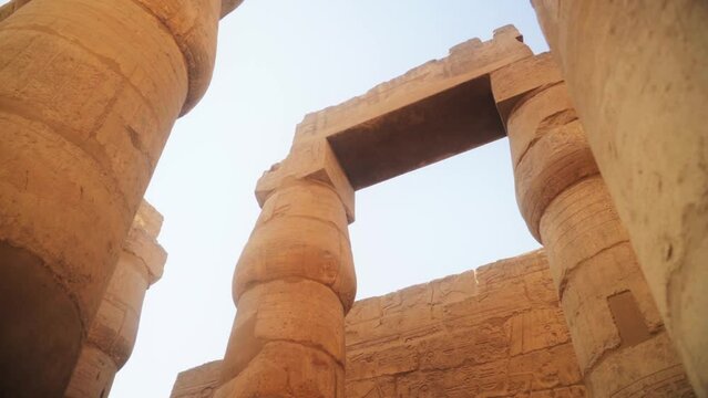 Low angle shot of tall Karnak Temple pillars. 
Slow sideways camera slide and rotation. 