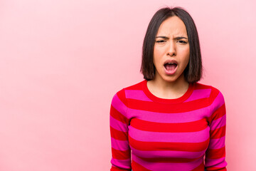 Young hispanic woman isolated on pink background shouting very angry, rage concept, frustrated.