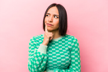 Young hispanic woman isolated on pink background contemplating, planning a strategy, thinking about the way of a business.