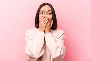 Young hispanic woman isolated on pink background shocked covering mouth with hands.