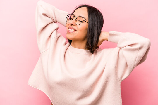 Young hispanic woman isolated on pink background feeling confident, with hands behind the head.