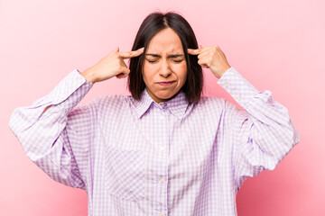 Young hispanic woman isolated on pink background focused on a task, keeping forefingers pointing head.