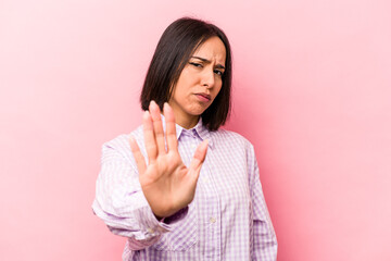 Young hispanic woman isolated on pink background rejecting someone showing a gesture of disgust.