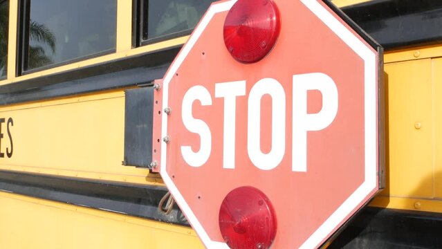 Red stop sign, yellow school bus in California, USA. Traffic warning on passenger schoolbus or shuttle in America. Public transportation safety on road. Caution or attention signage. Education concept
