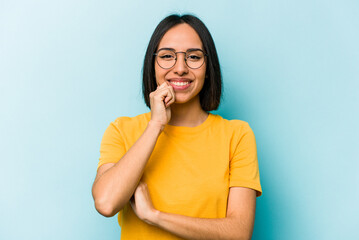 Young hispanic woman isolated on blue background smiling happy and confident, touching chin with hand.