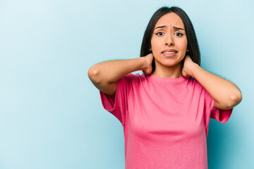 Fototapeta premium Young hispanic woman isolated on blue background touching back of head, thinking and making a choice.