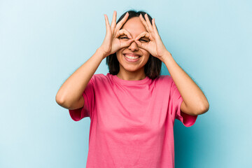 Young hispanic woman isolated on blue background excited keeping ok gesture on eye.