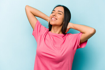 Young hispanic woman isolated on blue background feeling confident, with hands behind the head.