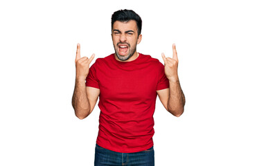 Hispanic man with beard wearing casual red t shirt shouting with crazy expression doing rock symbol with hands up. music star. heavy concept.