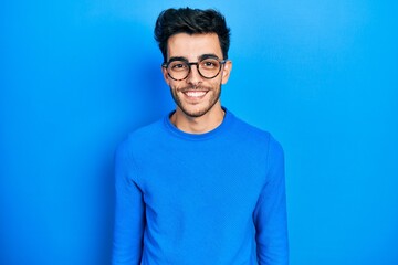 Young hispanic man wearing casual clothes and glasses with a happy and cool smile on face. lucky person.