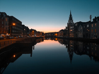 Fototapeta premium Sunset in Cork City Ireland business and classic buildings with reflection on the river