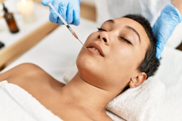 Obraz na płótnie Canvas Young hispanic woman having antiaging treatment at beauty center
