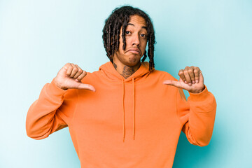 Young African American man isolated on blue background feels proud and self confident, example to...