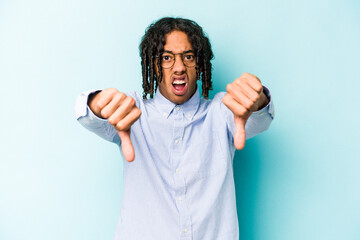 Young African American man isolated on blue background showing thumb down and expressing dislike.