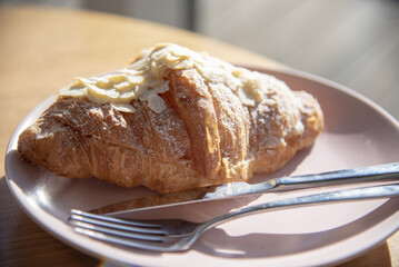 Almond sweet croissant on a plate on the table.