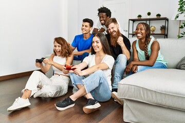 Group of young friends smiling happy playing video game at home.