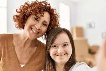 Mature mother and down syndrome daughter moving to a new home, standing by cardboard boxes