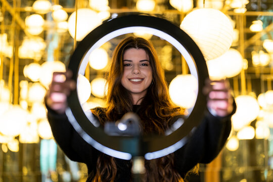 Smiling young woman holding ring right