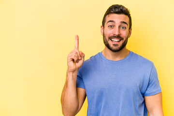 Young caucasian man isolated on yellow background showing number one with finger.