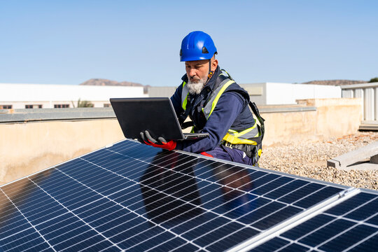 Technician with laptop working at solar power station
