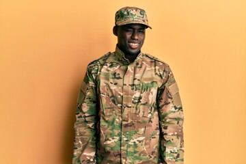 Young african american man wearing army uniform winking looking at the camera with sexy expression,...