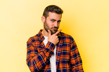 Young caucasian man isolated on yellow background contemplating, planning a strategy, thinking about the way of a business.