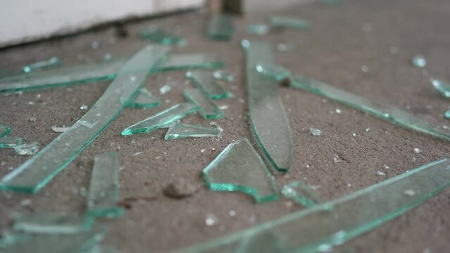 Multiple pieces of broken glass from a window lying on a floor. Vandalism. Burglary. Close up