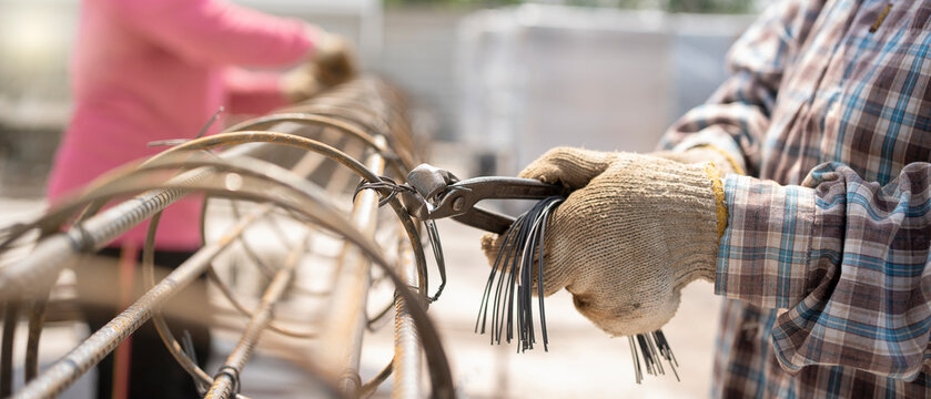 Construction worker hands securing steel bars with wire rod for reinforcement of concrete.Detail of infrastructure.using tools The use steel binding wires before casting concrete structure.