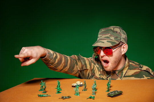 Army soldier playing with figurine toys against green background