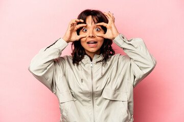 Young hispanic woman isolated on pink background keeping eyes opened to find a success opportunity.