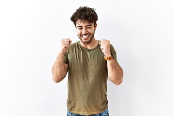 Fototapeta premium Hispanic man standing over isolated white background excited for success with arms raised and eyes closed celebrating victory smiling. winner concept.