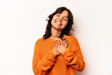 Young hispanic woman isolated on white background has friendly expression, pressing palm to chest. Love concept.