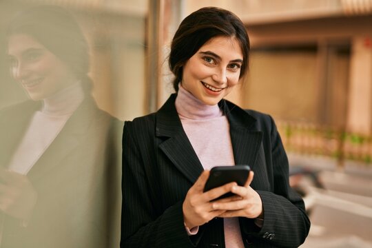 Young beautiful businesswoman smiling happy using smartphone at the city.