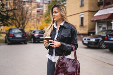 One young serious caucasian woman walking outdoor late for work in autumn day holding a cup of coffee real people copy space