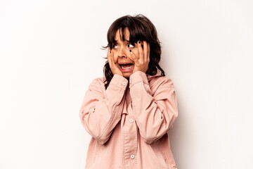 Young hispanic woman isolated on white background covering ears with hands trying not to hear too loud sound.