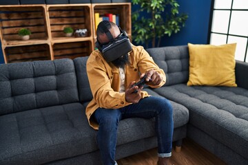 Young african american man playing video game using virtual reality glasses at home