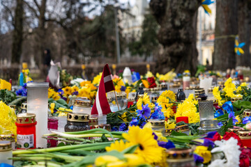 Candles, flowers and small Ukrainian flags on the pedestrian sidewalk. Protest action in Latvia...
