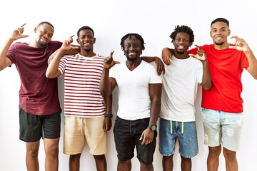 Young african group of friends standing together over isolated background smiling and confident gesturing with hand doing small size sign with fingers looking and the camera. measure concept.